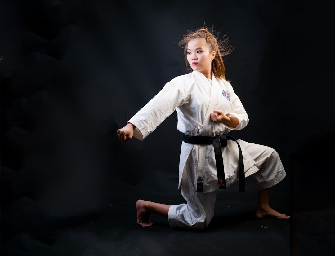 Karateka im weißen Gi demonstriert einen tiefen, knienden Stand